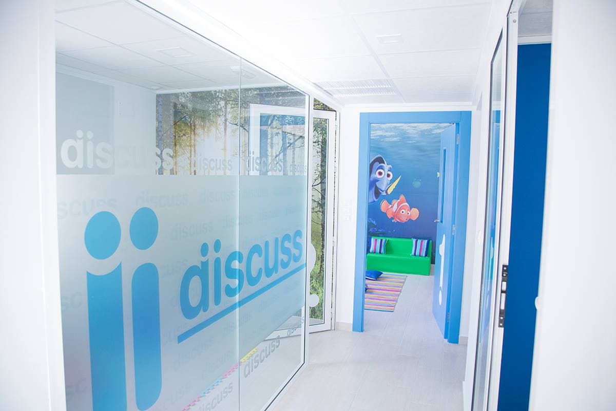 Pasillo interior de la academia Discuss Idiomas con vidriera corporativa y acceso a las aulas
