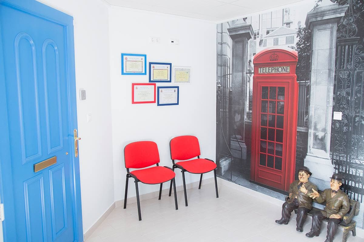 Sala de espera de Discuss Idiomas con diplomas y acreditaciones y decoración británica con cabina de teléfono roja de Londres